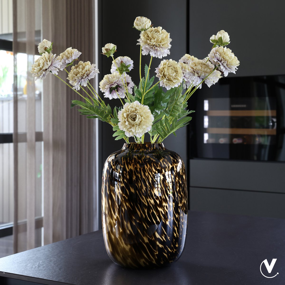 Vaas Artic Old Gold Cheetah met lichte bloemen op een donkere keukentafel