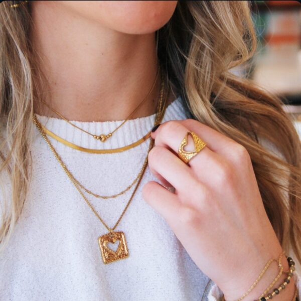 Slangenketting met hartje gedragen met andere gouden kettingen