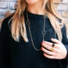 Lange schakelketting met ronde details gedragen op een trui