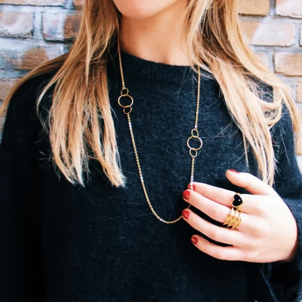 Lange schakelketting met ronde details gedragen op een trui