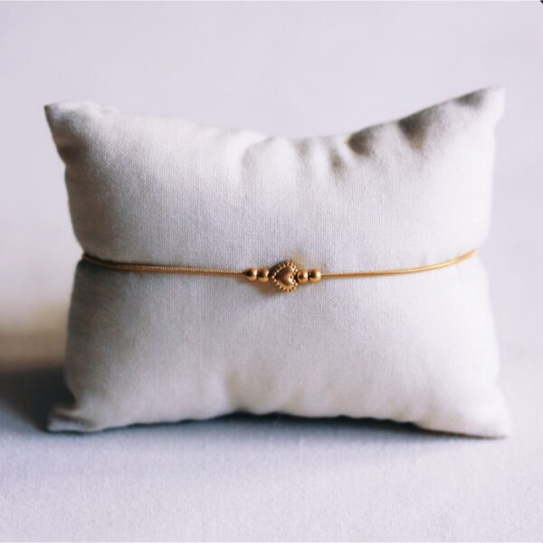Fijne slangenarmband met een gedetailleerde hartbedel en kleine kraaltjes in goud